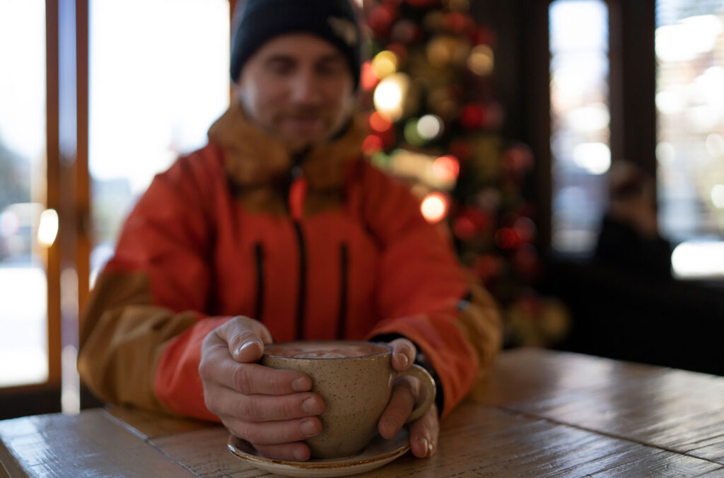 A man cradles a cup of hot chocolate in his hands at Fix Cafe in Whistler.