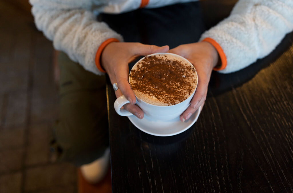 A man holds a mug of hot chocolate dusted with cocoa powder at Portobello in Whistler.
