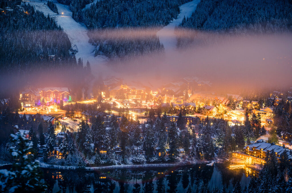 An evening shot of Creekside in the winter. You can see the ski runs weaving down the hill and Creekside Village glowing underneath.