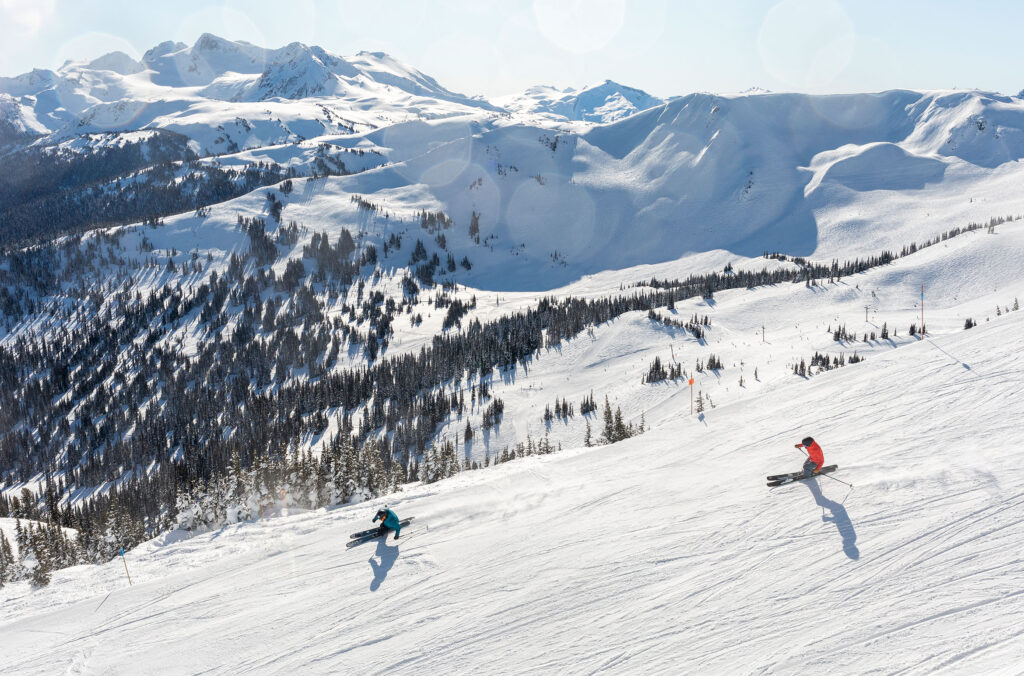 Two skiers enjoy the views on Whistler Mountain as they ride down the slopes.