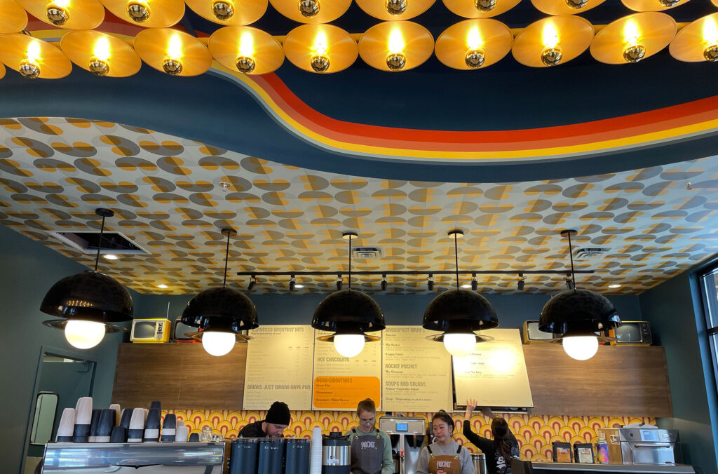 A photo of the coffee counter at Rockit Coffee in Whistler Creekside showing off the amazing lighting and colours.