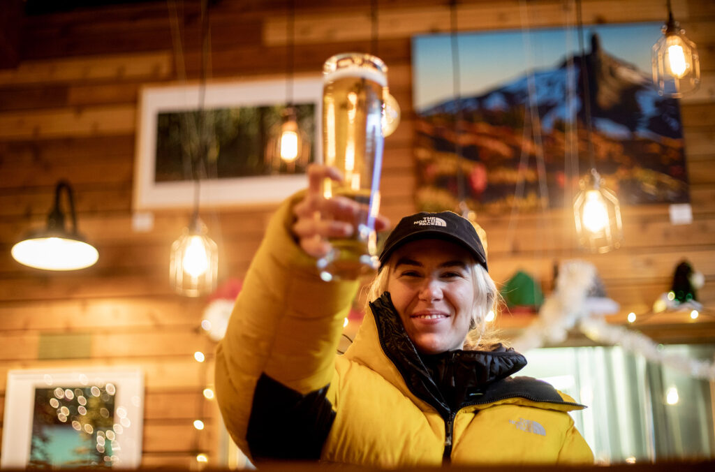 Ski athlete, Tonje Kvivik raises a glass of beer to the camera at Coast Mountain Brewing in Whistler.