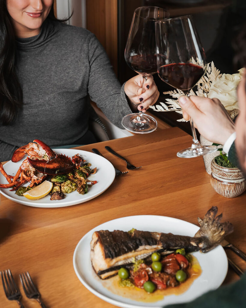 Two plates of delicious looking food, lobster and fish, at The Den at Nita Lake Lodge in Whistler.