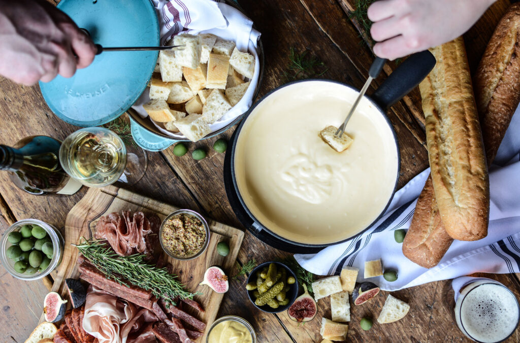 Hands reach into the fondue pot with skewers laden with bread at The Chalet, in Whistler.