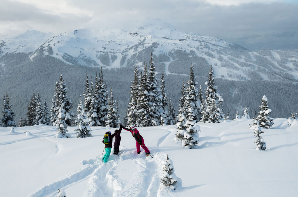 A group of teenagers high five on Whistler Blackcomb as they enjoy a day skiing.