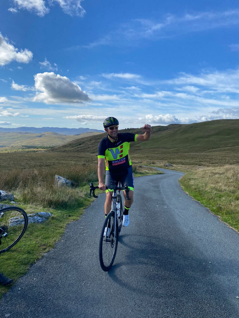 Matthew Barth raises his hand as he completes a race on his bike.