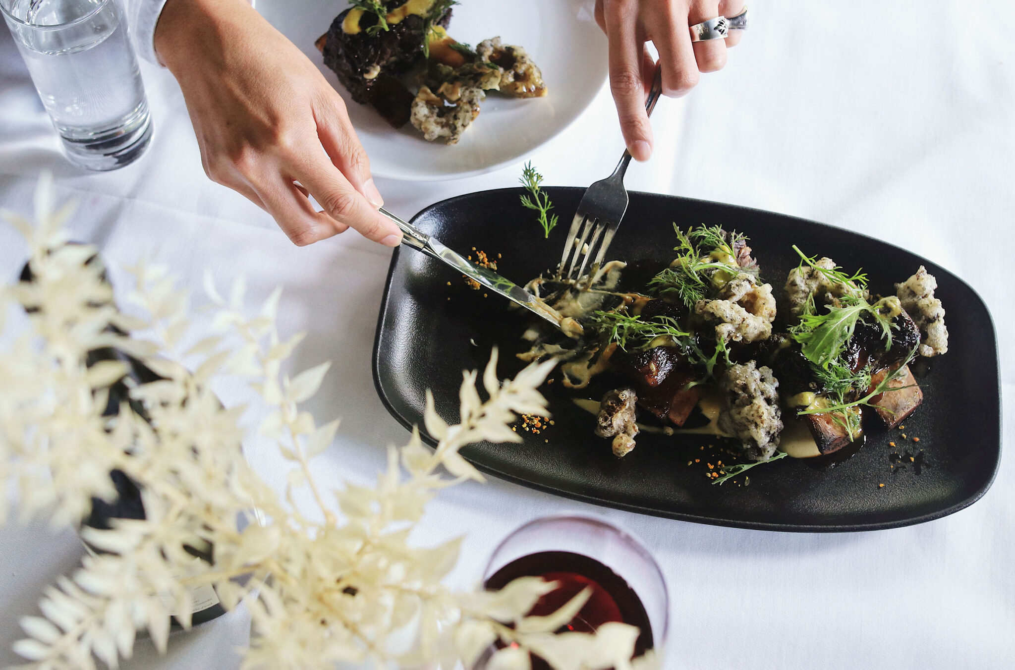 A diner takes foraged food from a share plate at Alta Bistro.
