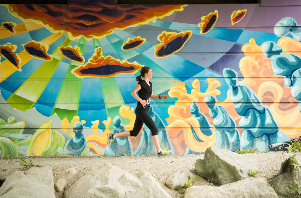 A runner passes by a beautiful mural on an underpass on the Whistler Valley Trail.