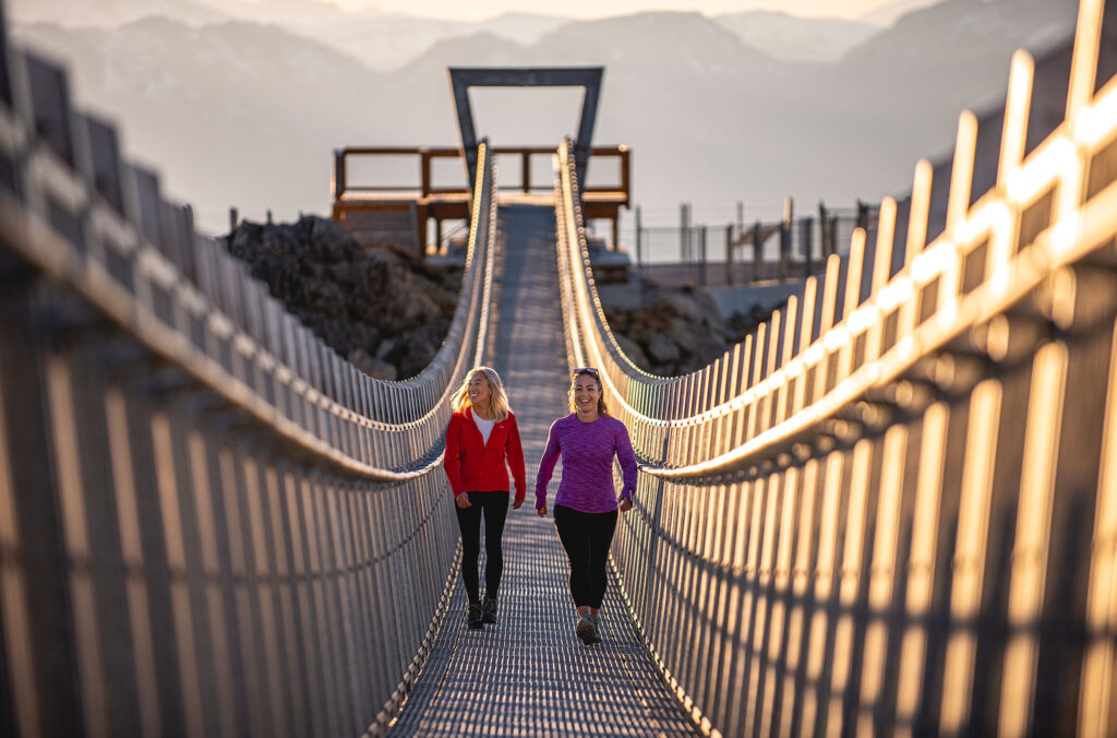 Two women walk across the Cloudraker Skybridge, Whistler's Suspension Bridge on Whistler Blackcomb.