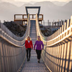 Two women walk across the Cloudraker Skybridge, Whistler's Suspension Bridge on Whistler Blackcomb.
