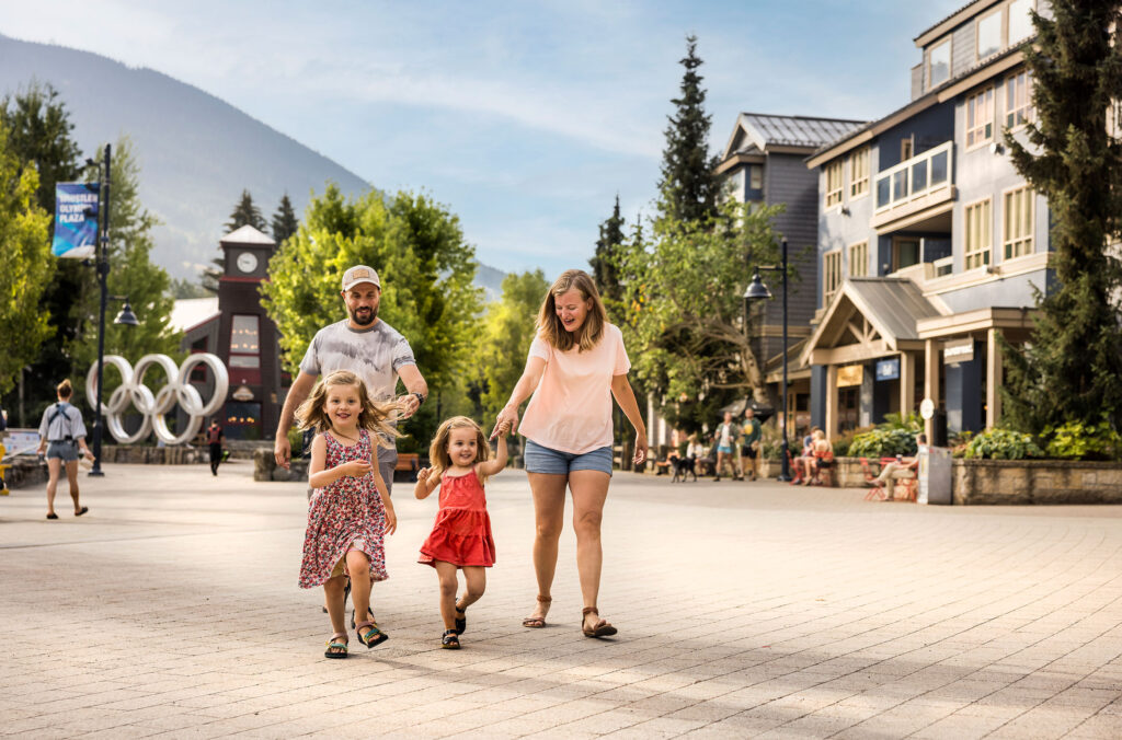 A family with young children walks through Whistler Village in the summer.