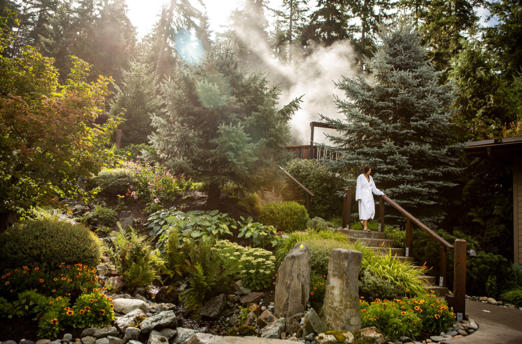 A woman makes her way down a staircase in a white bathrobe at the Scandinave Spa Whistler.