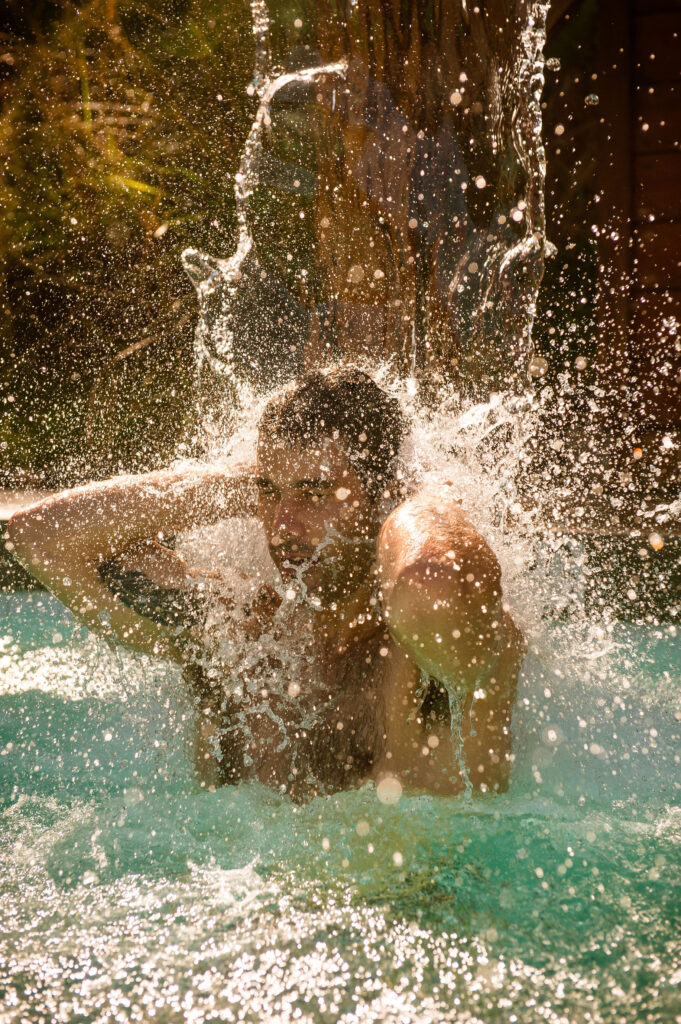 A man stands under a waterfall at the Scandinave Spa Whistler.