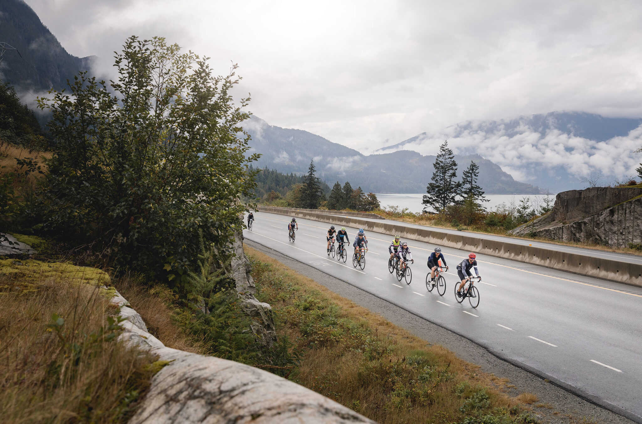 Cyclists make their way up the Sea to Sky in the GranFondo with the ocean on their left and the mountains ahead of them.