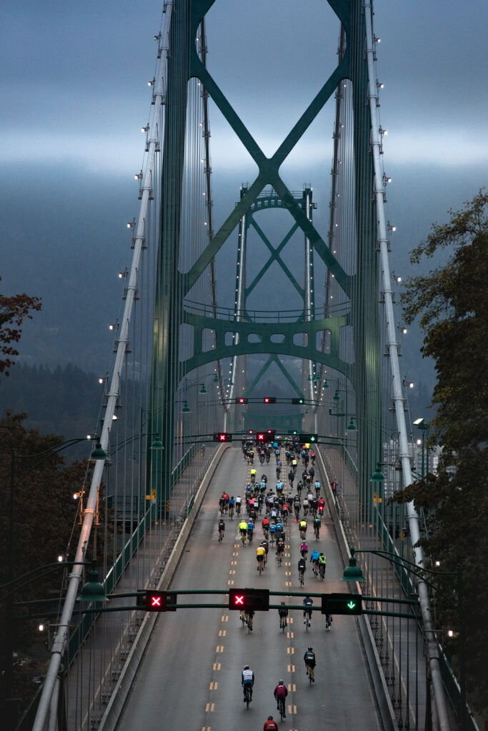 Cyclists doing the GranFondo Whistler make their way across the Lions Gate Bridge in Vancouver as the sun rises.
