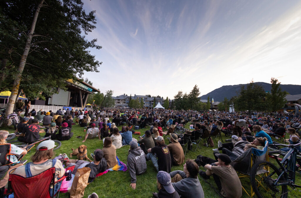 A crowd gathers on the grass at Whistler Olympic Plaza to watch Dirt Diaries during Crankworx Whistler.