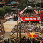 A shot from the hill looking out over the Redbull Joyride crowd as a bike athlete launches off a wooden bridge.