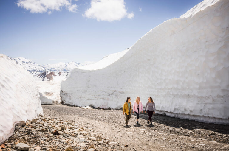 Three people walk between the snow walls on Whistler Blackcomb.