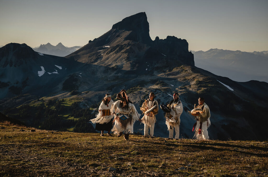 SLCC ambassadors and performers dance outside on their territory with Black Tusk in the background.