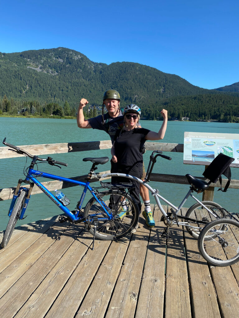 Miguel and Ineke explore Whistler's Valley Trail via bike and pose on the boardwalks over Green Lake.