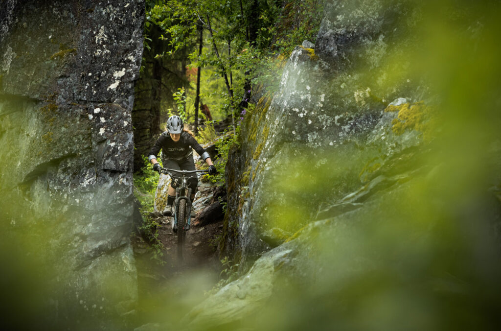 A mountain bike rider comes through the trees and rocks on the Howler trail in Whistler.