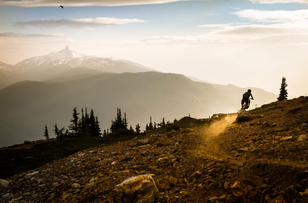 A mountain biker gets views out over the Coast Mountains and Black Tusk when they do the Top of the World trail on Whistler Mountain.