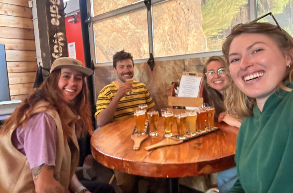 Four friends sit around a table at Whistler Brewing enjoying flights of beers.