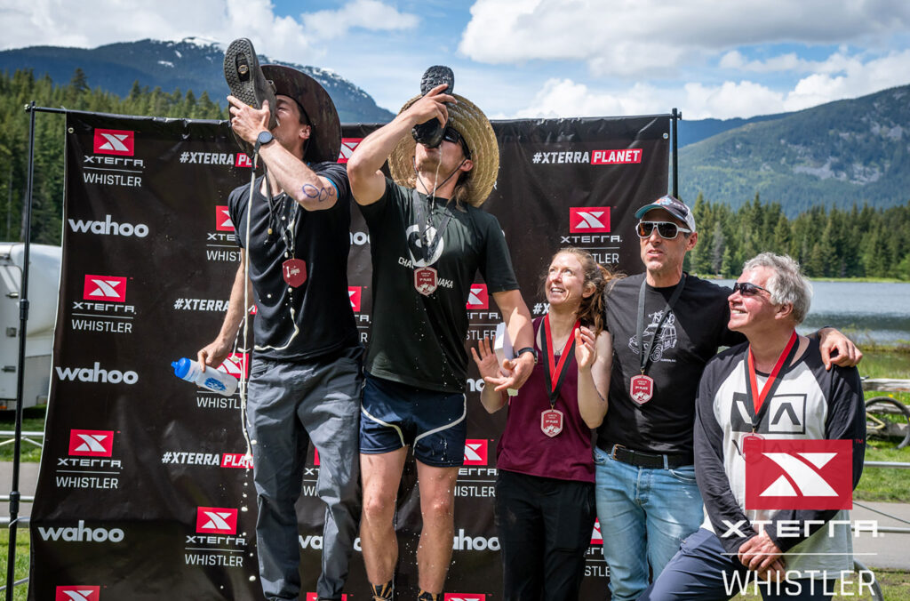 Two athletes celebrate their win at XTERRA Whistler by drinking beer out of their shoes.