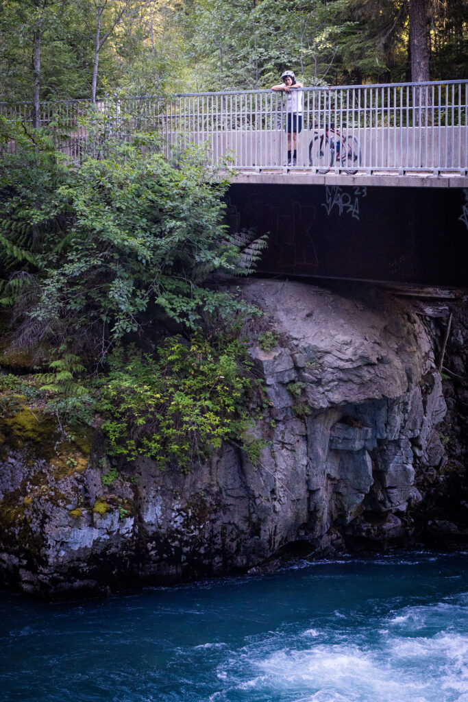 A gravel biker takes a moment to enjoy the rushing waters of Cheakamus River in Whistler.