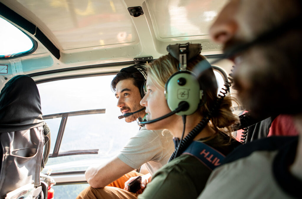 A group of bikers sit in a helicopter gazing out the windows at the view.