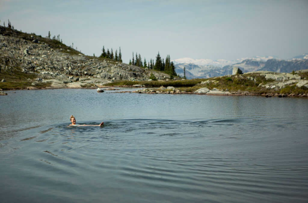 One of the riders has a quick dip in an alpine lake before continuing their ride down the mountain.
