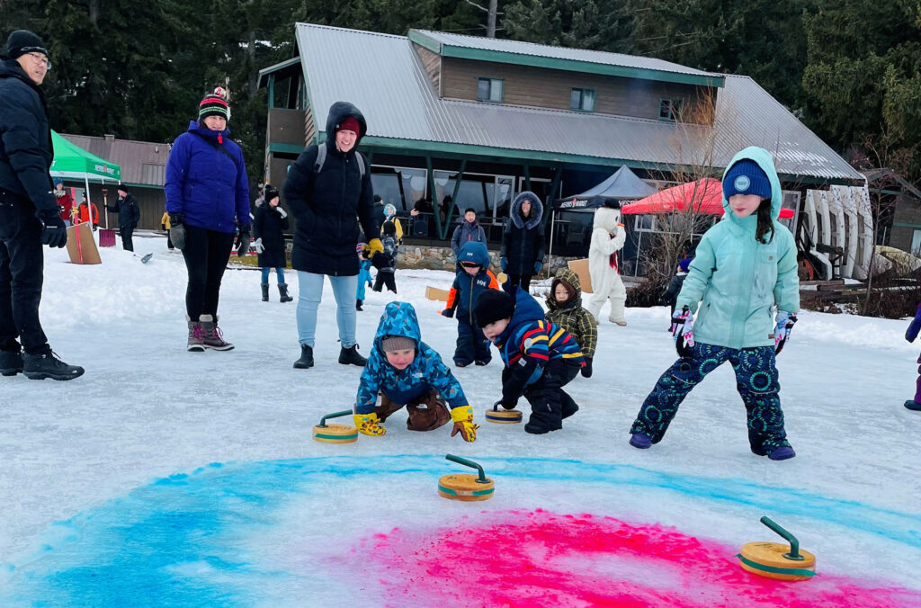 Kids play a game of curling outside the lodge at The Point during the Winter Carnival in Whistler.