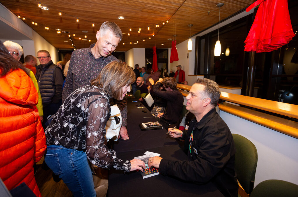 An author signs a copy of their book as an eager reader asks questions at the Whistler Writers Festival.