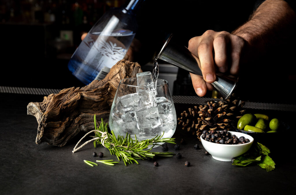 A bartender expertly crafts a cocktail inspired by Whistler's natural surroundings, with pine cones used as decorations.