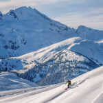 Two skiers make their way down a snowy slope on Whistler Blackcomb.
