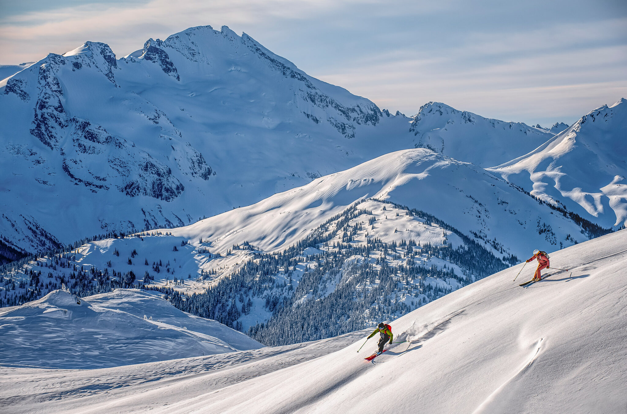 Two skiers make their way down a snowy slope on Whistler Blackcomb.