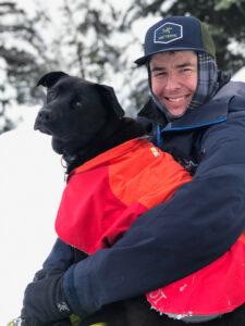 Fire and Ice Show athlete, Jessie, holds his dog in the snow.