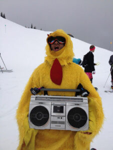 Fire and Ice Show athlete, Mauro is dressed in a chicken suit holding a boom box on the snowy slopes.