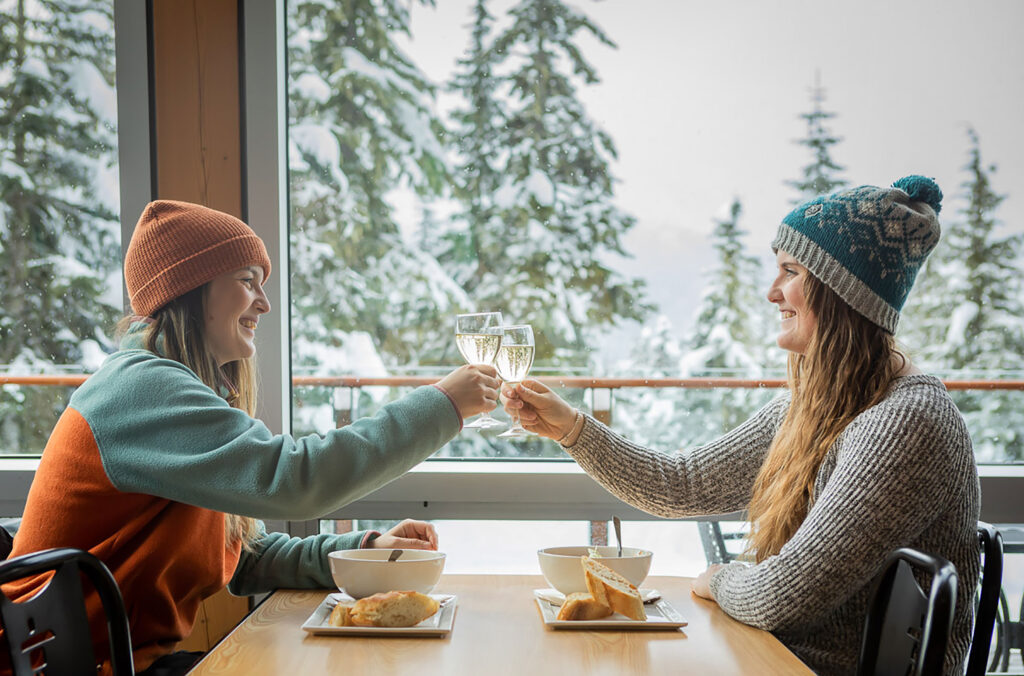 Two women enjoy a glass of wine at the Day Lodge at Whistler Olympic Park after cross-country skiing.