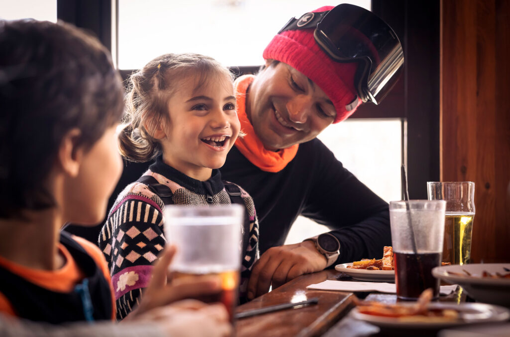 A father and his two kids enjoy apres in Whistler after skiing.