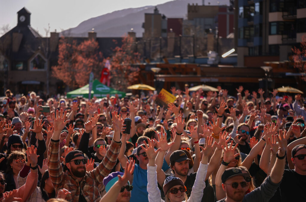 A crowd of people raise their hands in the air to live music happening at the bottom of Whistler Mountain during the World Ski and Snowboard Festival.