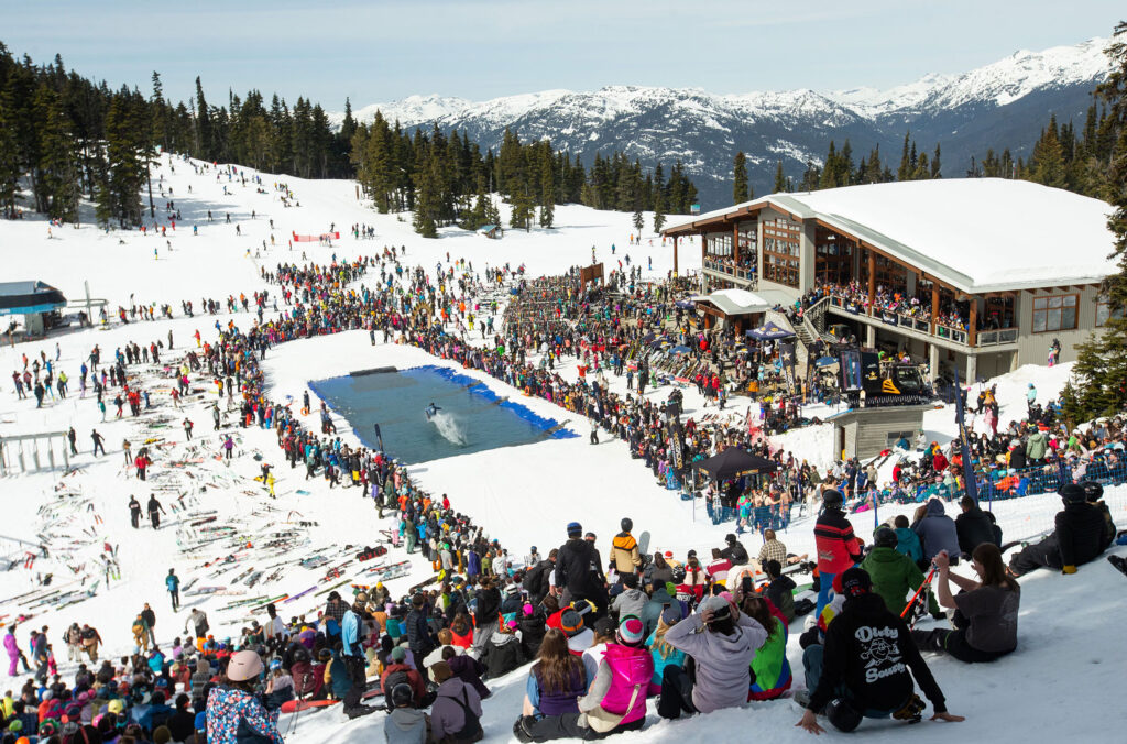 A crowd looks on as skiers and snowboarders try to get across a pool of water at the Slush Cup, part of Whistler's World Ski and Snowboard Festival. 