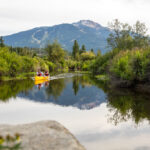 Two people navigate the River of Golden Dreams via canoe in the summer months in Whistler.