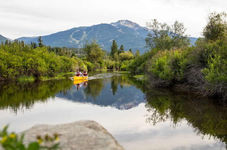 Two people navigate the River of Golden Dreams via canoe in the summer months in Whistler.