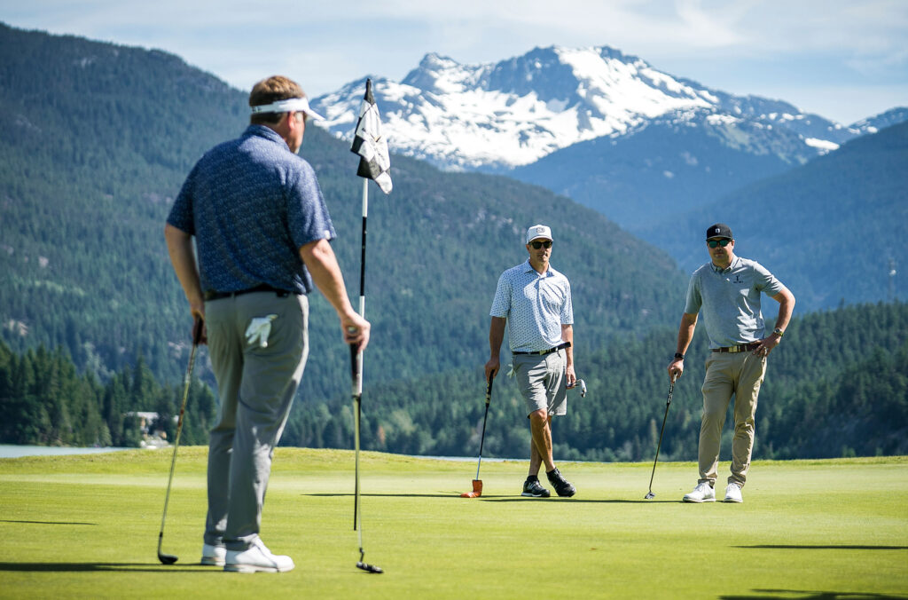 Three golfers enjoy the sunshine and mountain views at the Nicklaus North Golf Course in Whistler.