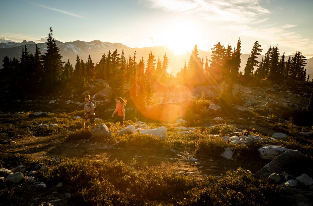 Two people hike through the high alpine on Whistler Blackcomb in the summer.