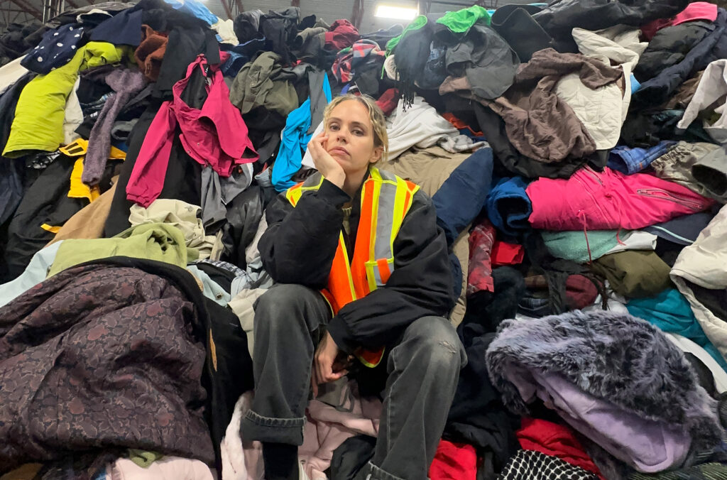 Amy Rafferty, co-owner of F as in Frank, sits amidst a huge pile of second hand and vintage clothing.