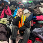 Amy Rafferty, co-owner of F as in Frank, sits amidst a huge pile of second hand and vintage clothing.