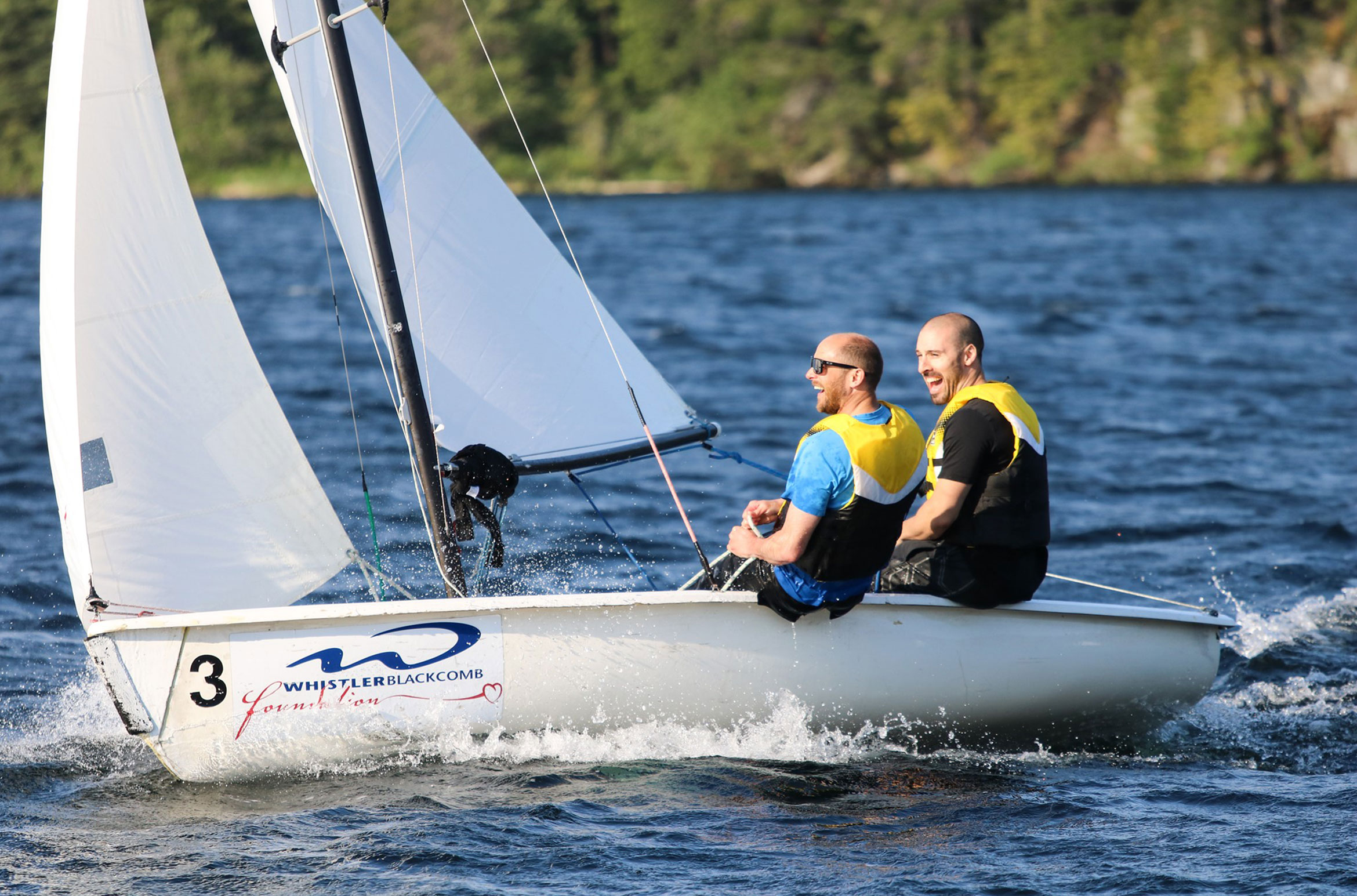 Two people sail in Whistler in the summer sun on Alta Lake.