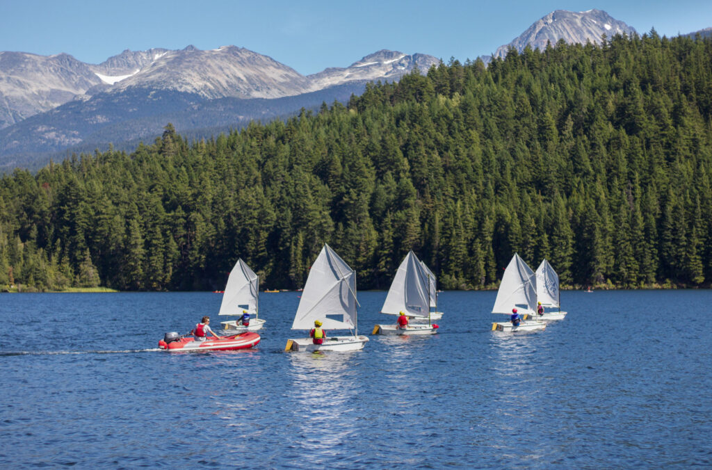Five sailboats make their way across Alta Lake, part of a kids' summer camp in Whistler.